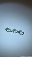 Three lagoon blue-green faceted Paraiba tourmaline stones on white background