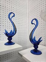 Both cobalt blue glass swans side by side on shelves