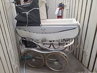 Side view of white Silver Cross pram with black hood showing full chassis and wheels