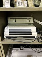 Front view of Akiles binding machine showing punch section, roller inserter and power cord