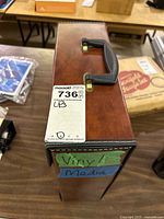 Top view of brown faux-leather LP case showing handle, latch and lot label