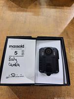 Body camera in open box showing device front and lot label