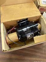 Motor in box showing housing, mounting bracket, wiring leads and nameplate