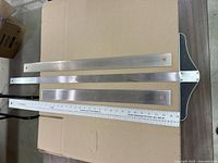 All four rulers laid out: T-square, two stainless straight edges, aluminum ruler