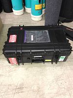 Top view of black hard equipment case with latches, handle and labels