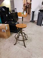 Full view of drafting stool showing wood seat and backrest with metal base