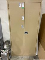 Front view of beige metal cabinet showing double doors and locking handle