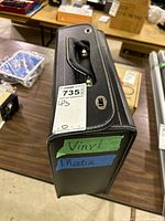 Black faux-leather carrying case closed, side view with handle and latches