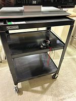 Front view showing three shelves, casters, Luxor logo