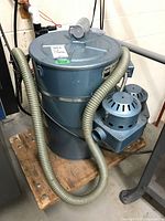 Front view of blue NSI Filtex dust collection unit on wooden dolly with hose attached