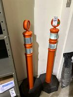 Full view of both orange posts seated in black octagonal bases