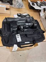 Camcorder resting on black carry bag, eyepiece, controls and included battery visible