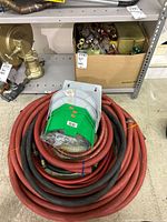 Overall lot showing coiled hoses, brass valve, box of fittings on shelf