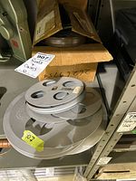 Stacked aluminium film reels and open box containing reels on shelving
