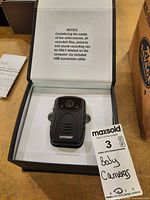 Camera in open box showing front lens and branding