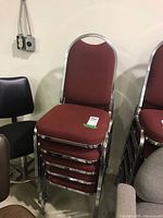 Stack of burgundy padded chairs showing chrome frames