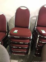 Stack of burgundy banquet chairs showing chrome frames and padded seats