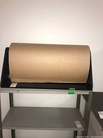Front view of tabletop dispenser holding kraft paper roll on shelving