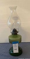 Full view of green glass oil lamp with chimney
