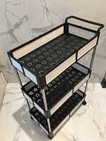 Angled top view showing three perforated shelves, handle and casters