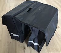 Top view of black double pannier showing PVC cover, handle slot, and compartment openings