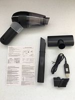 All items laid out: vacuum body, two nozzles, USB cable, brush, manual