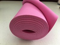 Rolled end view of pink yoga mat showing textured foam layers