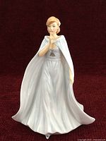 Front view of porcelain figurine showing gown, cape, gesture