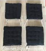 Four black square cushions laid flat, showing top quilting and ties