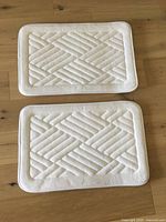 Top view of both white bathroom mats showing quilt pattern