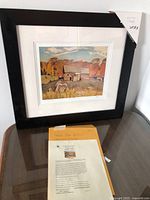 Framed print and certificate on table