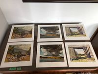 Six prints laid out on table, two rows of three