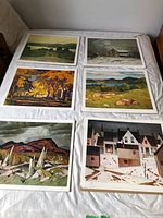 Six different A.J. Casson landscape prints laid out on bed, showing overall lot