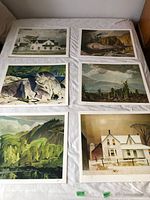 Six different A.J. Casson prints laid out on a bed