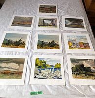 Overview of nine of the Casson prints laid out on a bed