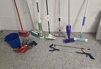Group shot of all cleaning items including vacuum, bucket, brooms, mops, grabbers