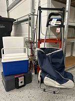 Group shot showing hand truck, utility cart, coolers, toolbox, lock box, fishing rods on rack