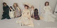 Group shot of seven porcelain dolls and two stands