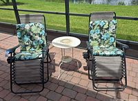 Two lounge chairs with cushions and side table on patio
