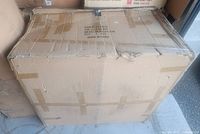 Closed cardboard carton labeled with item data, box edges damaged