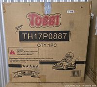 Closed cardboard box showing TOBBI branding, model TH17P0887, and ride-on car graphic