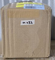 Sealed cardboard shipping box labelled M032 containing shade sail