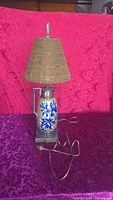 Lamp with shade, angled view showing blue floral ceramic body, metal hardware, cord
