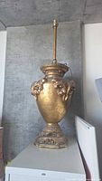 full view of ornate antique-gold lamp base showing urn design and overall height