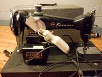 Left side view of Kenmore model 1120 sewing machine on case, spool, light and cords visible
