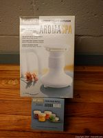 Retail box of Homedics AromaSpa diffuser standing behind Body Basics four-pack refill box