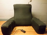 Front view of black backrest pillow with remote and cable visible