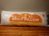 Body pillow in original plastic packaging on floor