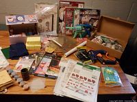 Overview of entire assortment on table showing glue guns, paint, sponges, molds, stencils, kits, ribbon and manuals