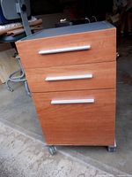 front view of filing cabinet showing three drawers, handles, wheels